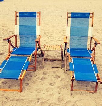 Relaxing beach scene with two blue sun loungers on sandy shore, perfect for tropical vacations.