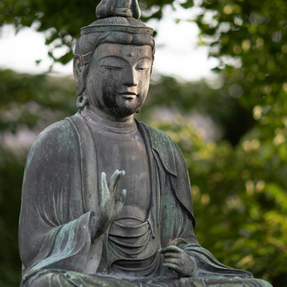 Buddha statue amidst lush greenery in Tokyo's Shinjuku City.